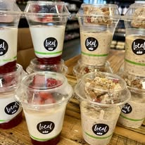 Local-branded cups of yogurt parfaits and overnight oats topped with fruit and granola